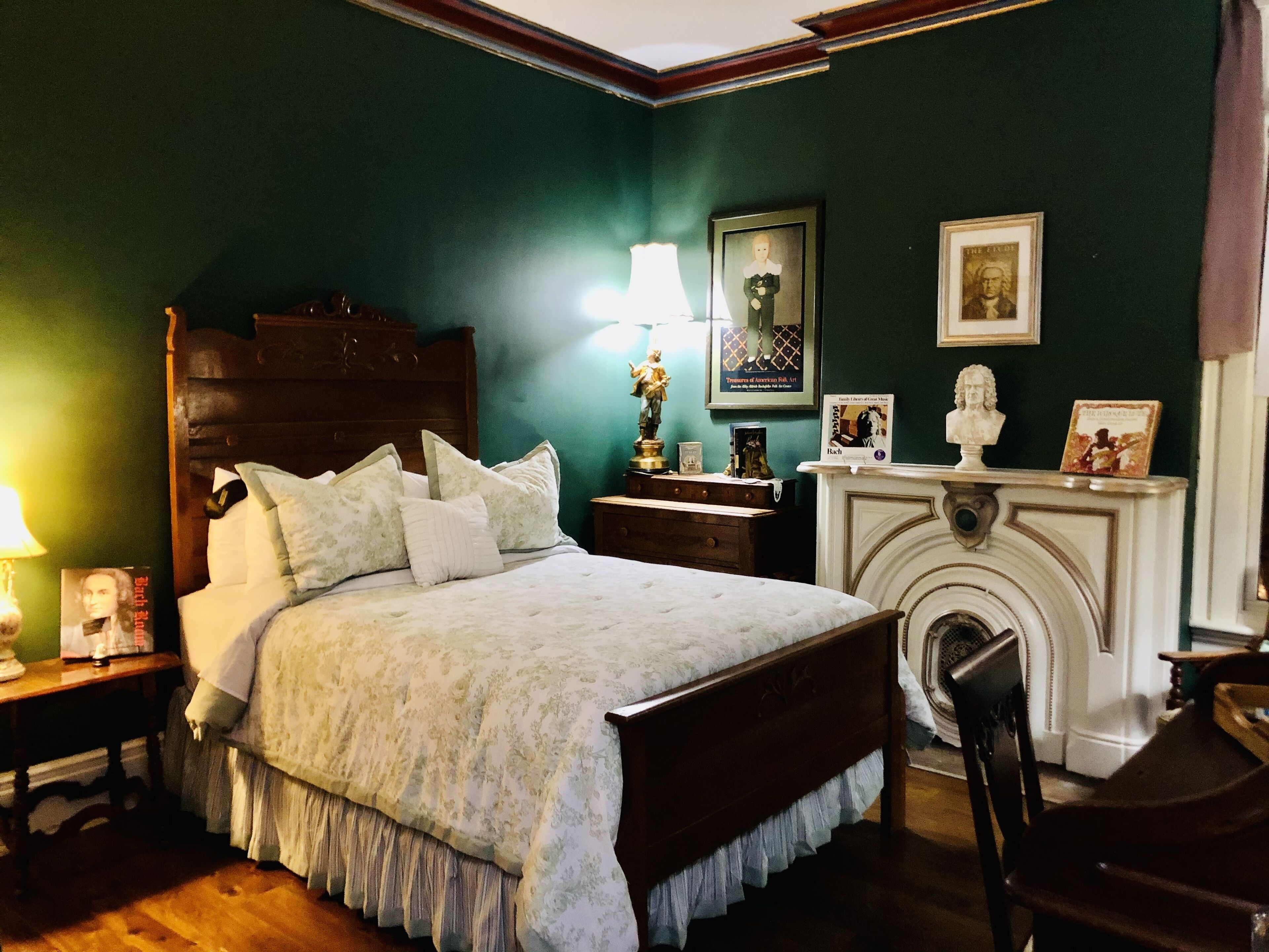 Un dormitorio tradicional con cama con dosel, mesita de noche con lámpara, chimenea y cuadros en las paredes.