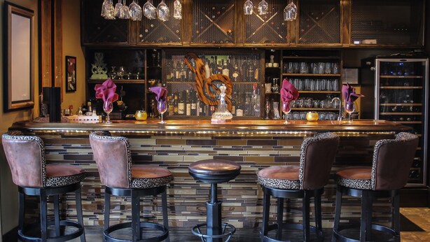 A bar area with a counter, stools, and hanging light fixtures.