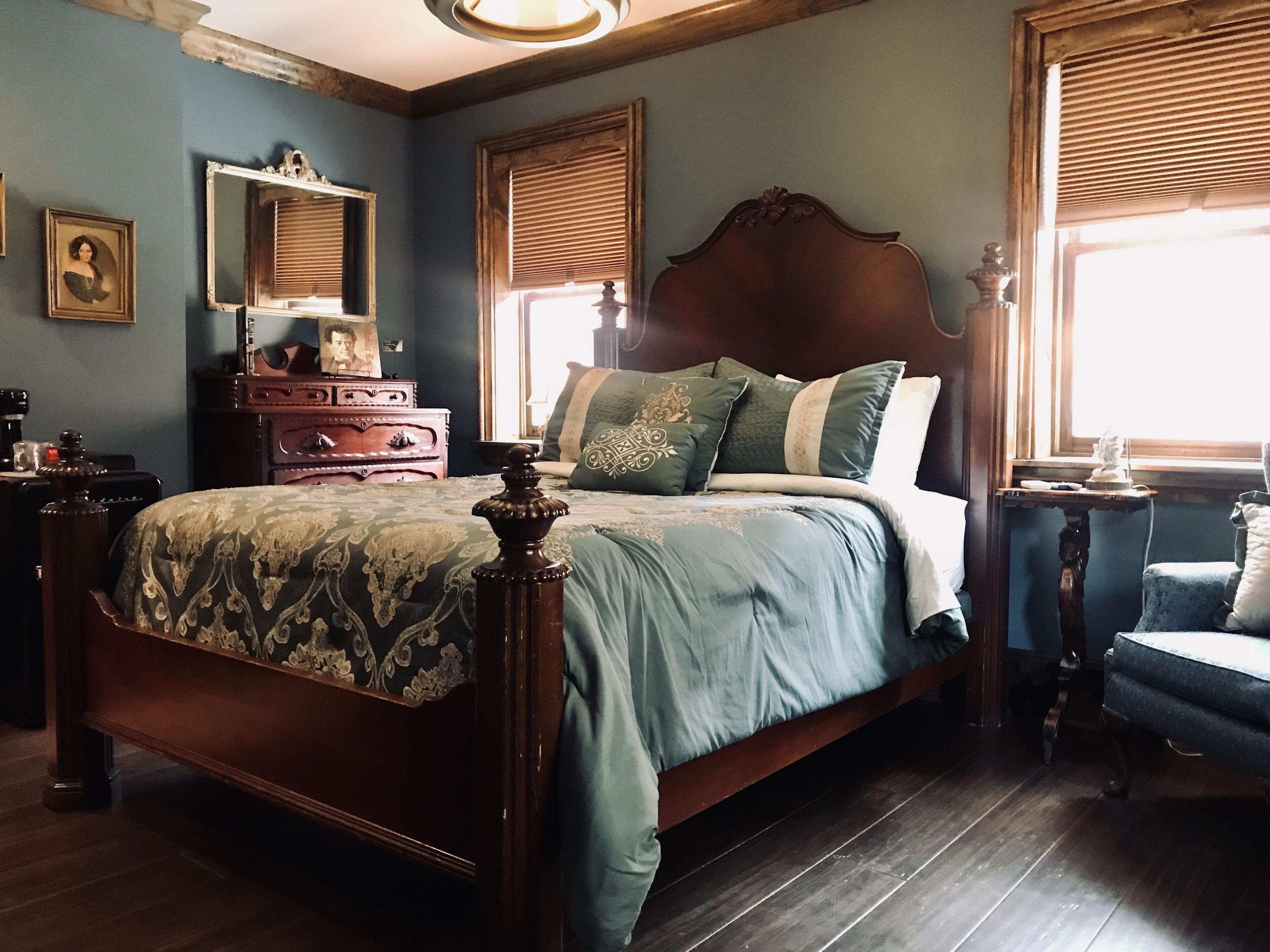 Ein traditionell eingerichtetes Schlafzimmer mit einem hölzernen Bett, einem Schminktisch, einem Spiegel und einem Fenster mit Jalousien.