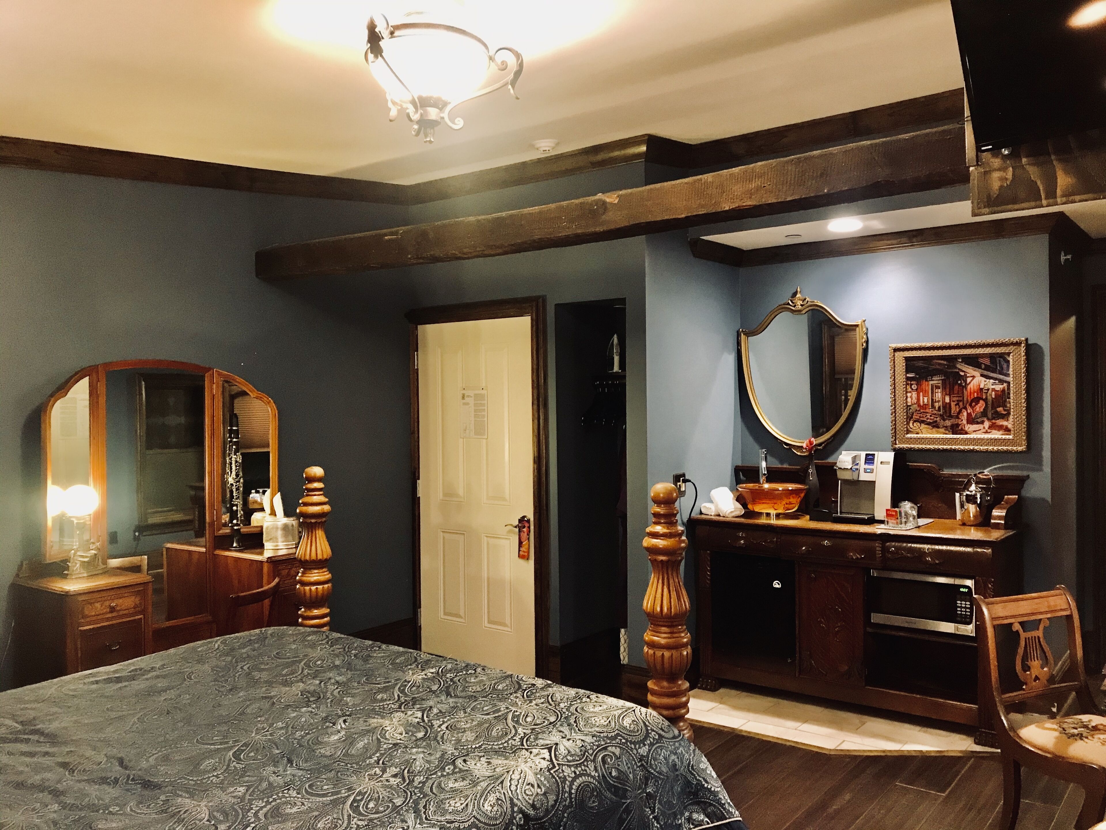 A bedroom with a bed, dresser, mirror, and artwork on the wall.