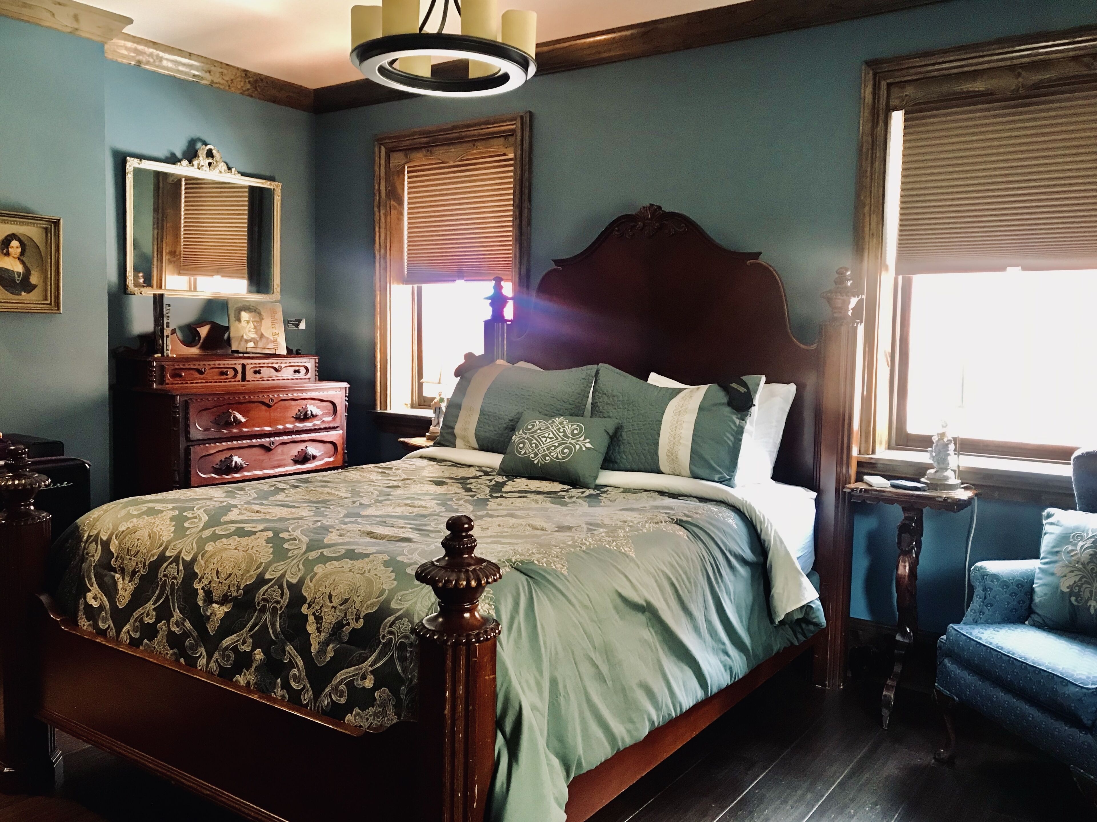 A bedroom with a large bed, dresser, and a chair.