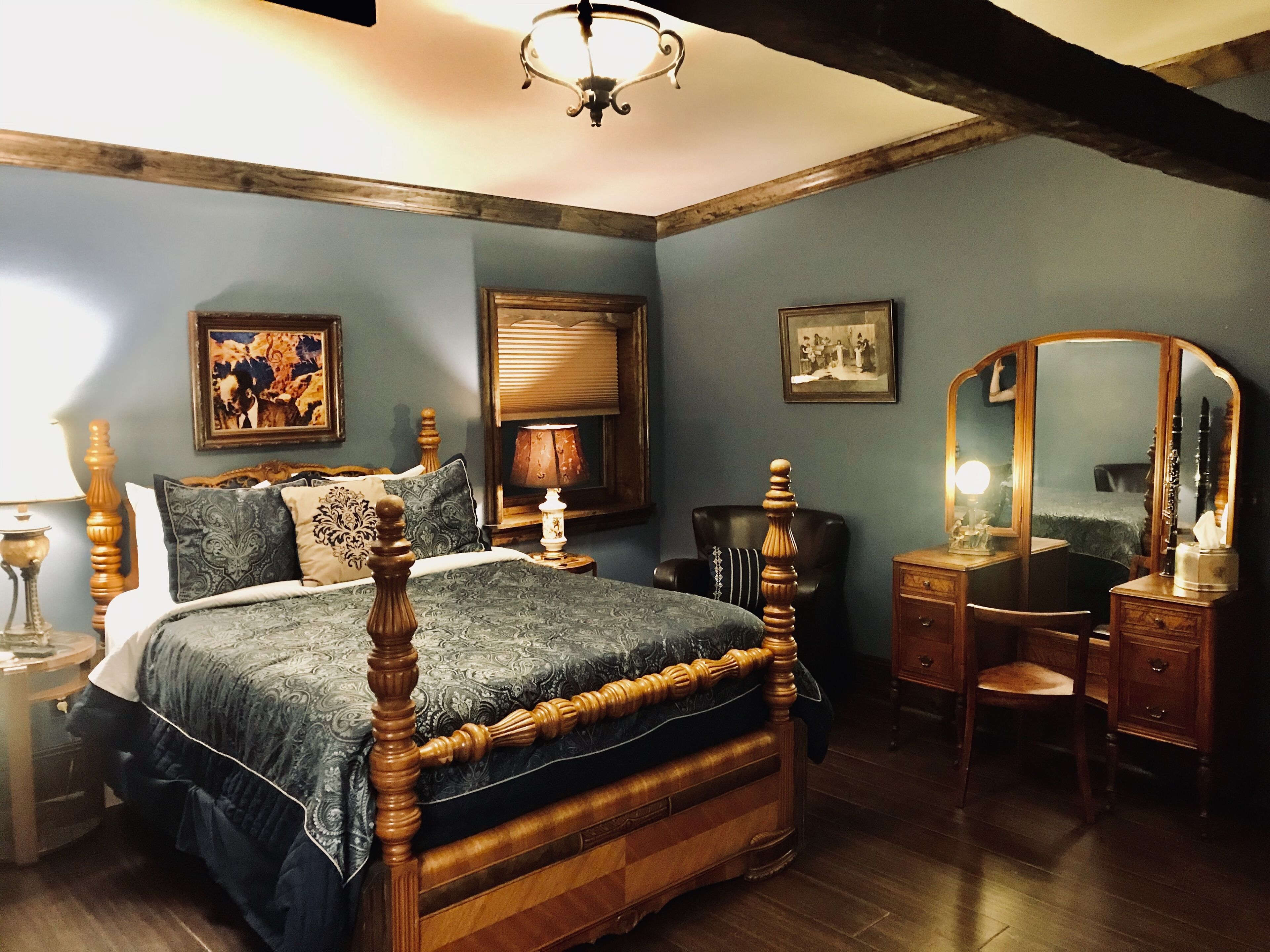 A bedroom with a four-poster bed, a dresser, a chair, and a mirror.