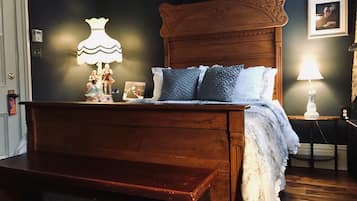 A bedroom with a wooden bed, a nightstand with a lamp, and a dresser.