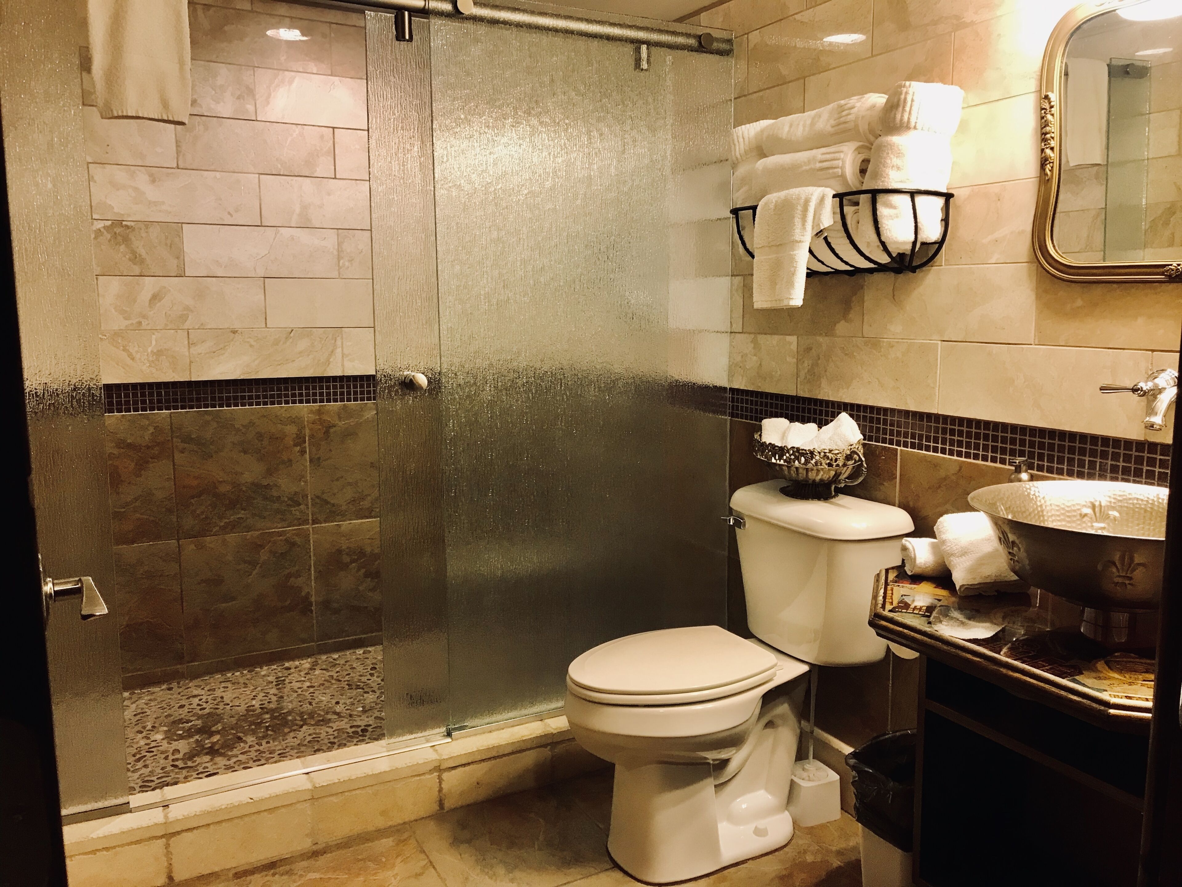 Une salle de bain dotée d’une douche à parois de verre, de toilettes et d’un lavabo avec un receveur décoratif.