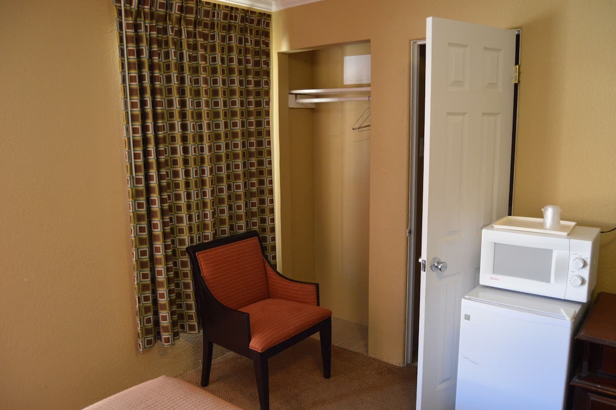 A compact room with a single chair, a microwave, and a partially open door leading to another room.