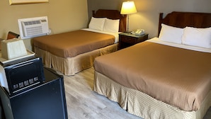 Une chambre d’hôtel avec deux lits, un bureau avec un ordinateur, une lampe et un tableau au mur.