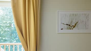 A room with a window, a curtain, and a framed artwork on the wall.