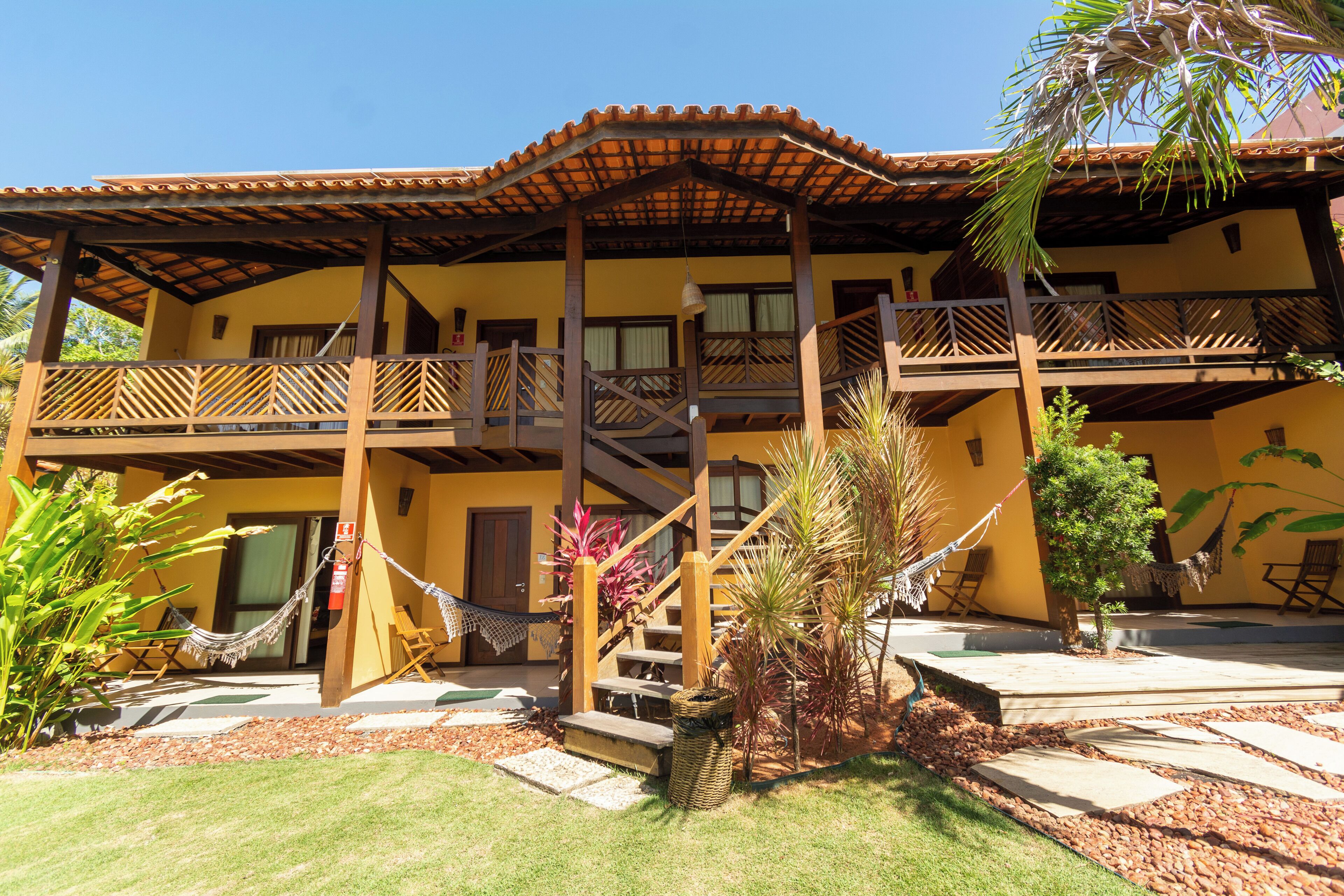 A two-story building with a balcony, a staircase, and a hammock.