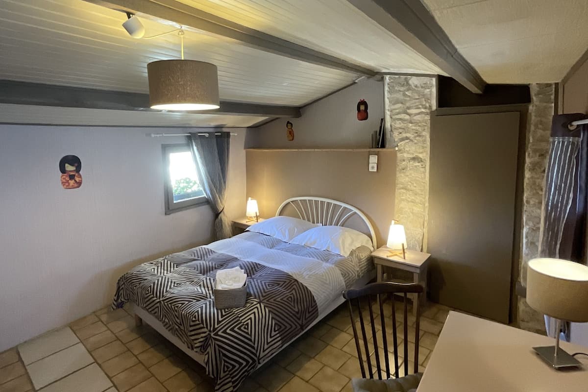 Une chambre à coucher avec un lit, une chaise, une table et une lampe.
