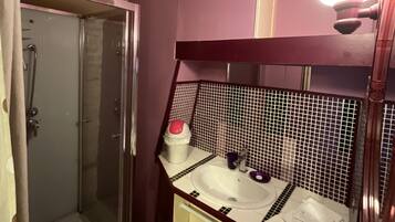Een badkamer met een douche, wastafel en spiegel.