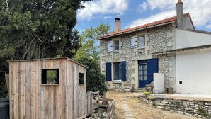 A rustic stone building with a wooden shed in a rural setting.