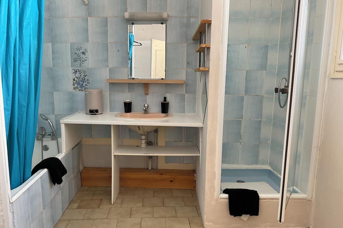 Une salle de bain équipée d’un lavabo, d’un miroir, d’une douche et d’un porte-serviettes.