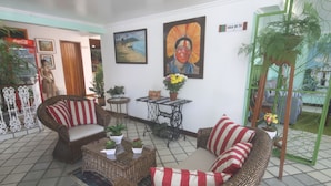 A furnished living room with wicker furniture, a coffee table with plants, and artwork on the walls. - Hotel Terra Mater (Porto Seguro)