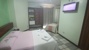 A hotel room with a bed, a TV, a small table with a chair, and a window with curtains. - Hotel Terra Mater (Porto Seguro)
