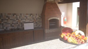 A kitchen with a brick oven, wooden cabinets, and a tiled backsplash. - Hotel Terra Mater (Porto Seguro)