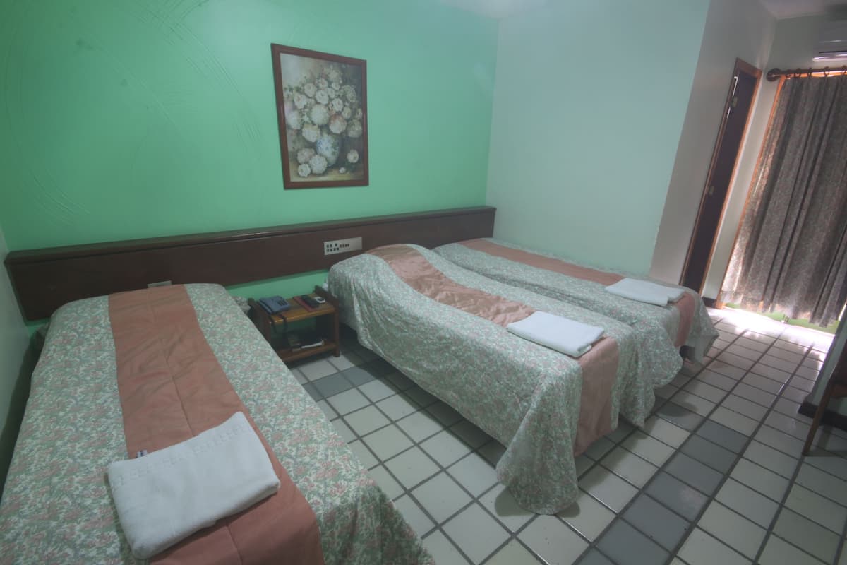 A hotel room with two beds, a nightstand, a painting on the wall, and a tiled floor.