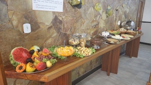 A buffet table with various food items and a stone wall with fish decorations. - Hotel Terra Mater (Porto Seguro)