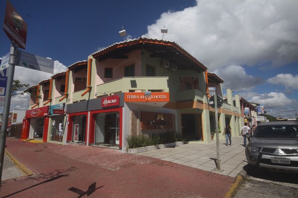 A hotel with a red and white facade, multiple floors, and a tiled roof. - Hotel Terra Mater (Porto Seguro)
