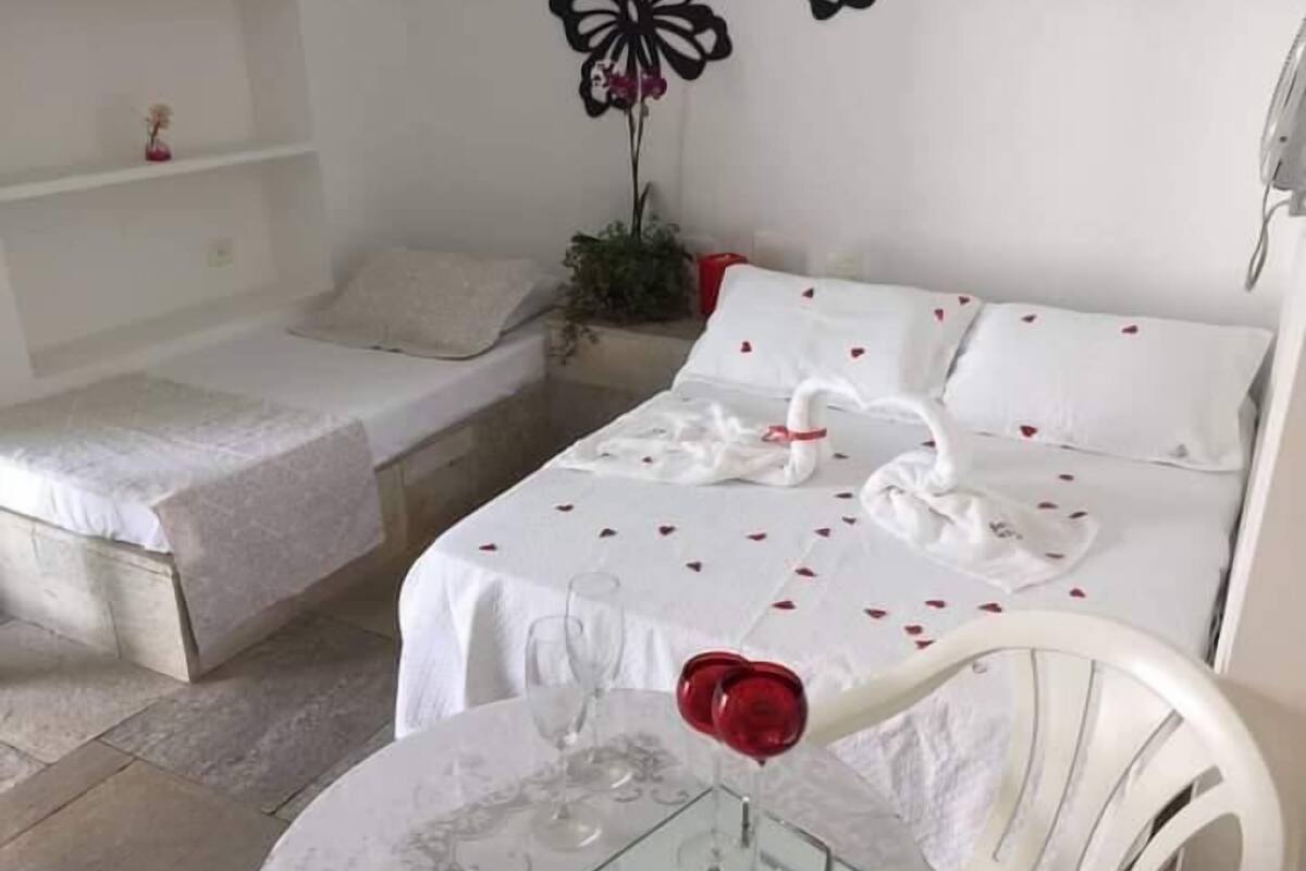 Une chambre d’hôtel avec un lit, une petite table avec un verre et une chaise.