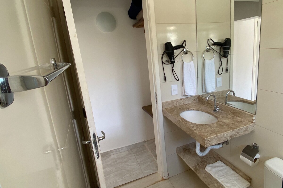 Une salle de bain avec un double lavabo, un miroir, un porte-serviettes et des toilettes.