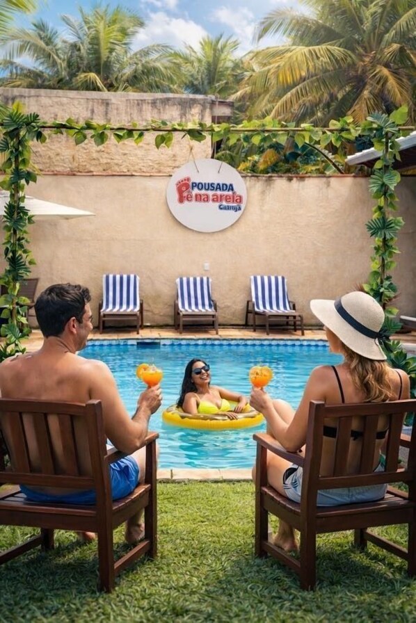Un espace aménagé au bord de la piscine, avec des chaises longues, une pancarte indiquant « Pousada Rio na Areia » et une piscine.