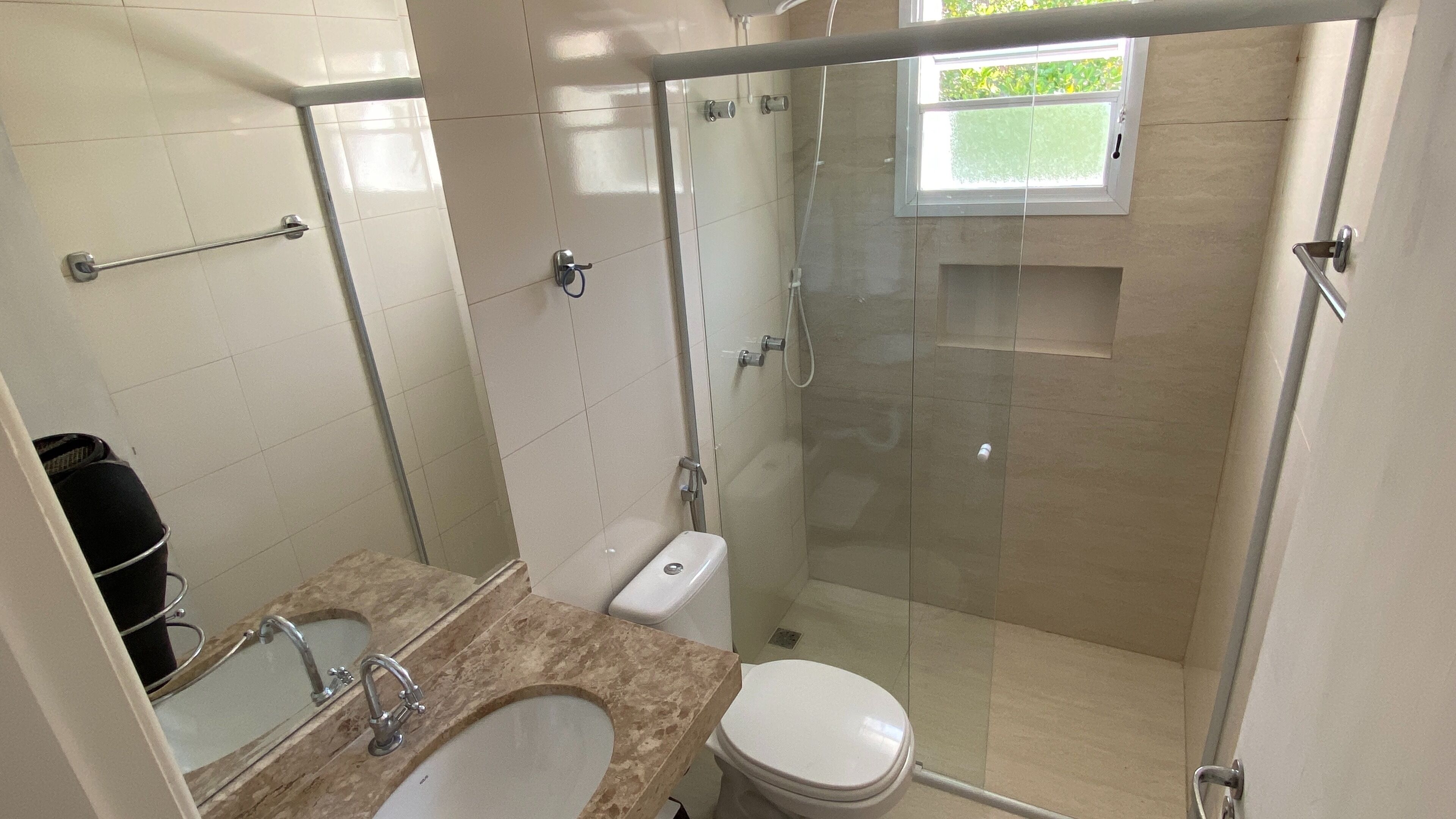 A bathroom with a glass-enclosed shower, a toilet, a sink, and a mirror.