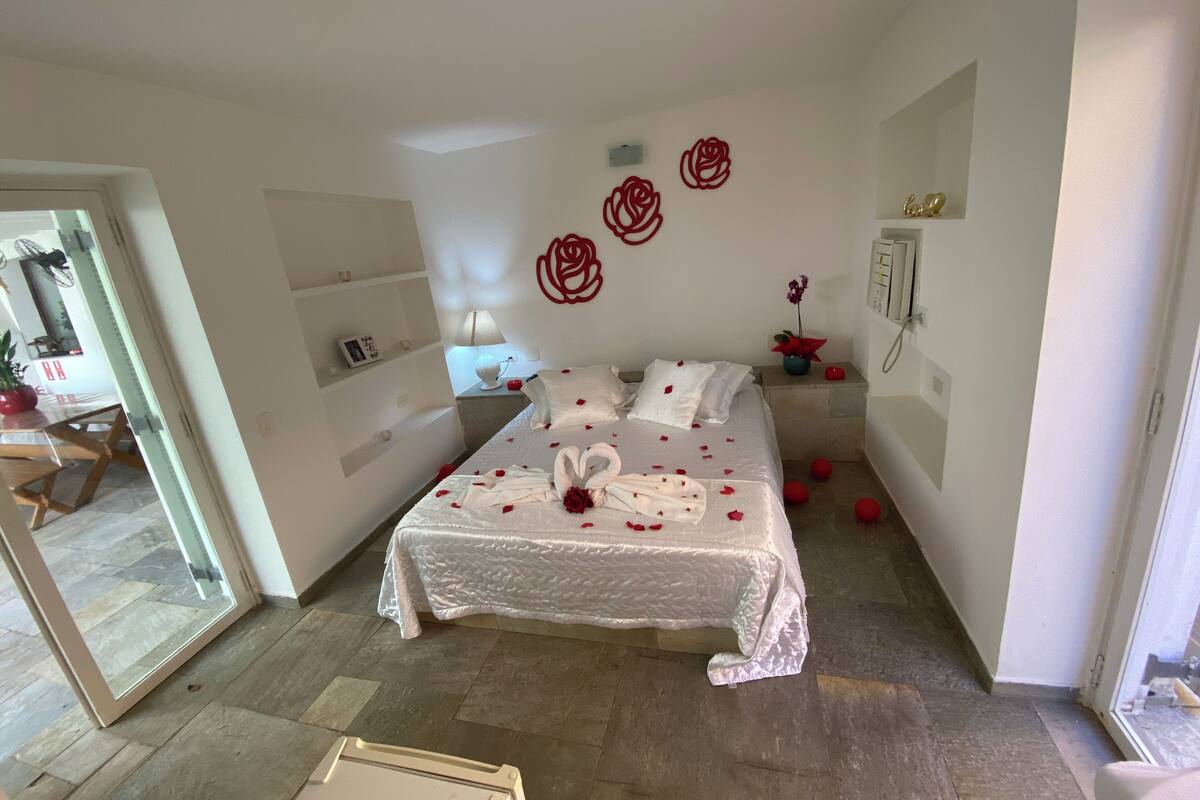 Une chambre à coucher avec un lit, une table de chevet, une lampe, une plante en pot et un élément décoratif mural.
