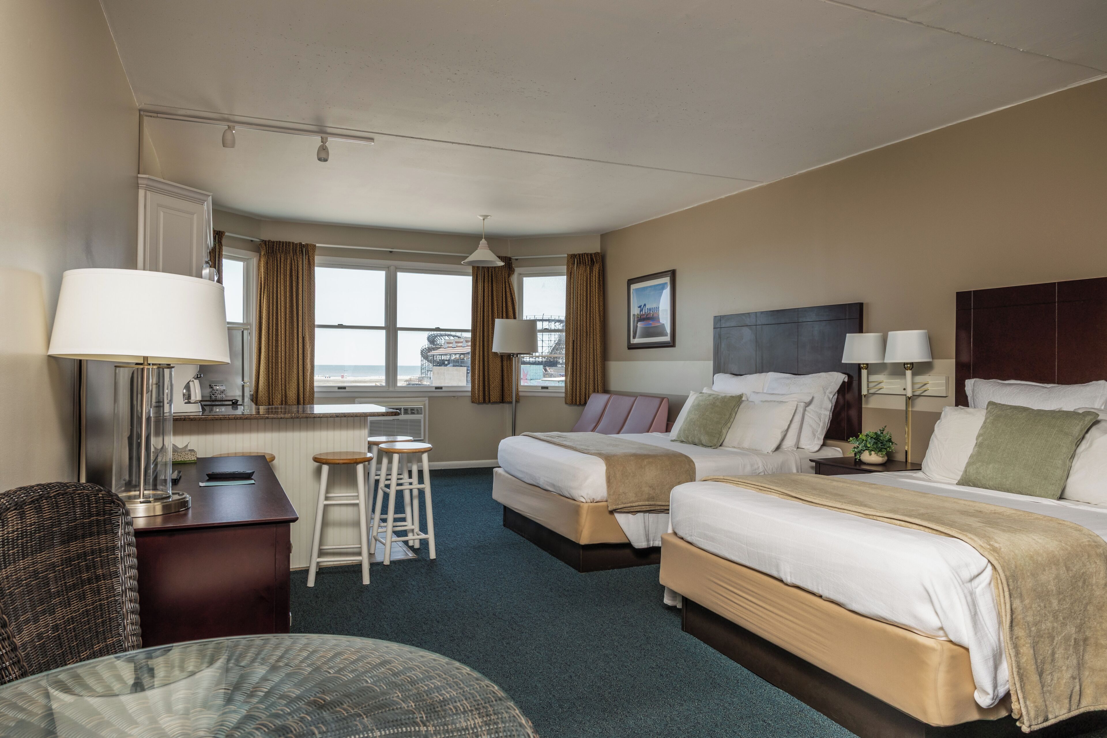 A hotel room with two beds, a desk, a chair, a window with curtains, and a view of the cityscape.