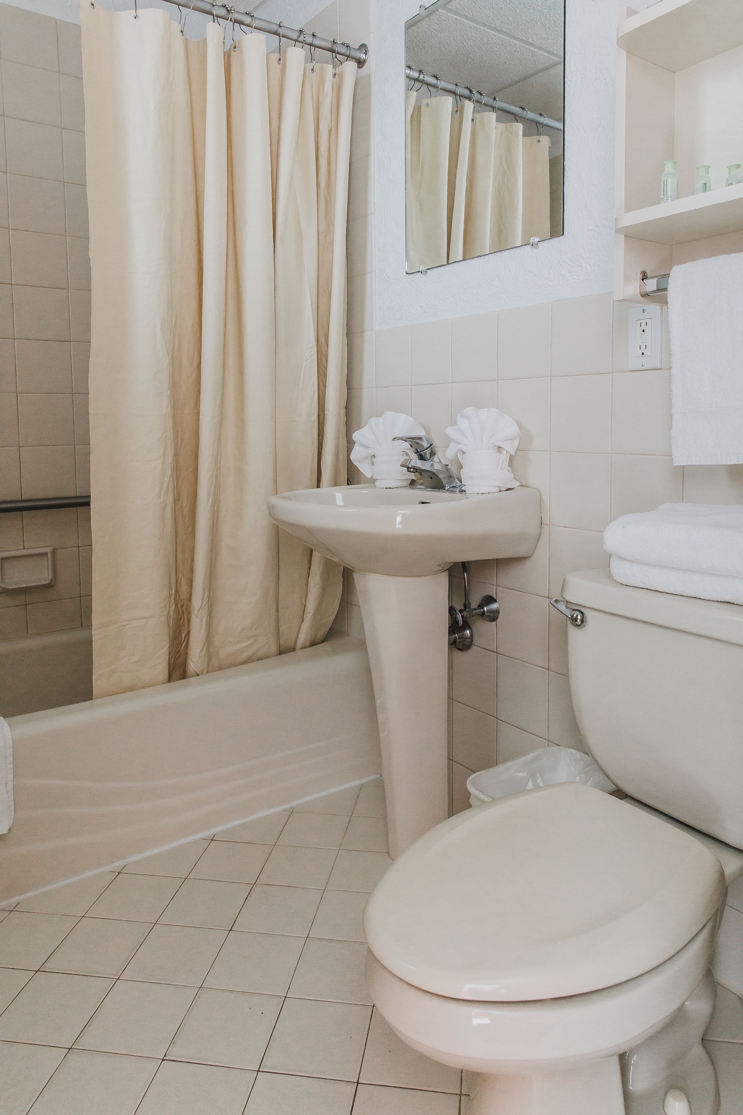A bathroom with a bathtub, toilet, sink, and a mirror above the sink.