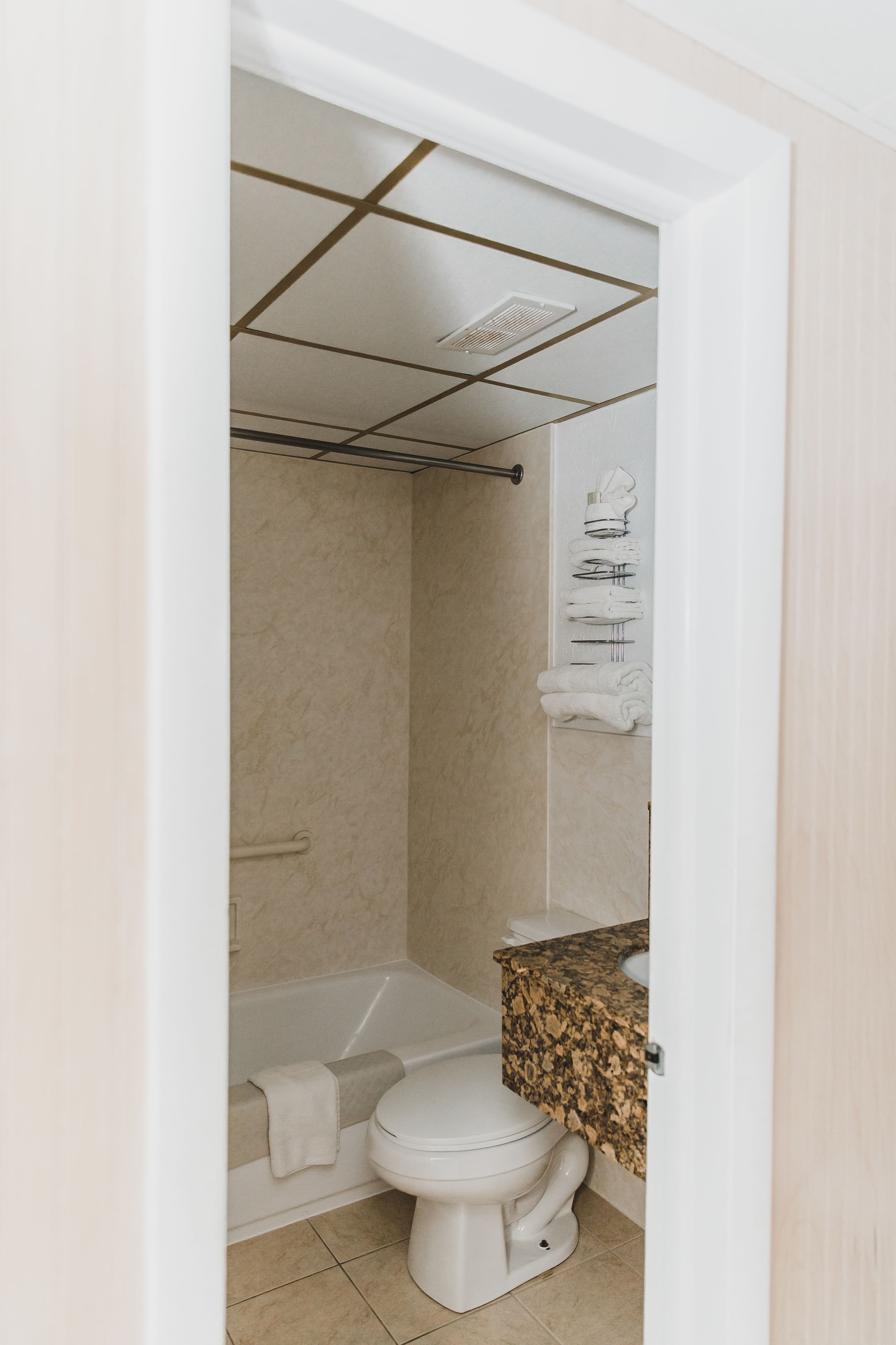 A bathroom with a bathtub, toilet, and a vanity with a granite countertop.
