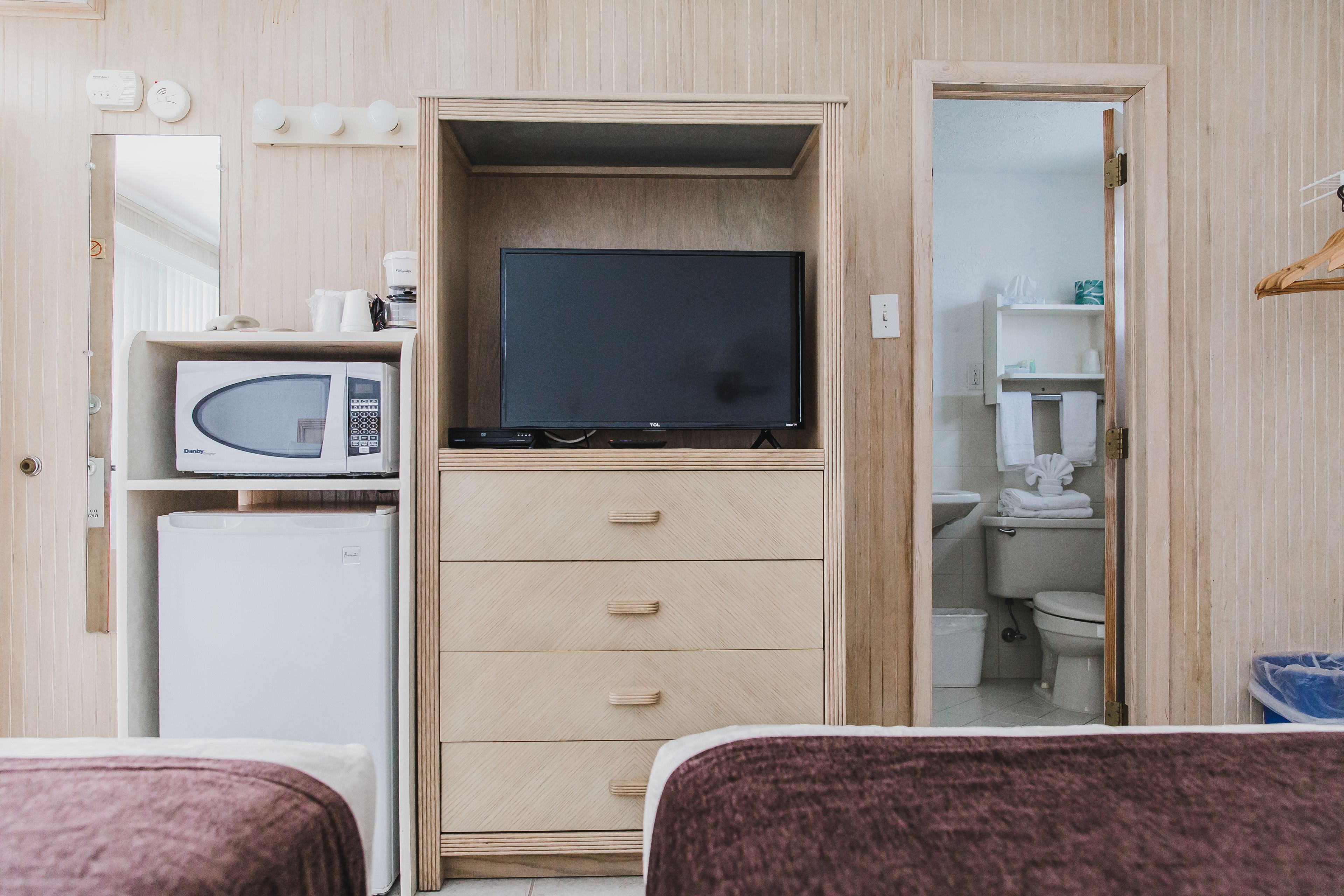 Ein kleines Zimmer mit einem Bett, einer Mikrowelle, einem Fernseher und einem kleinen Kühlschrank.
