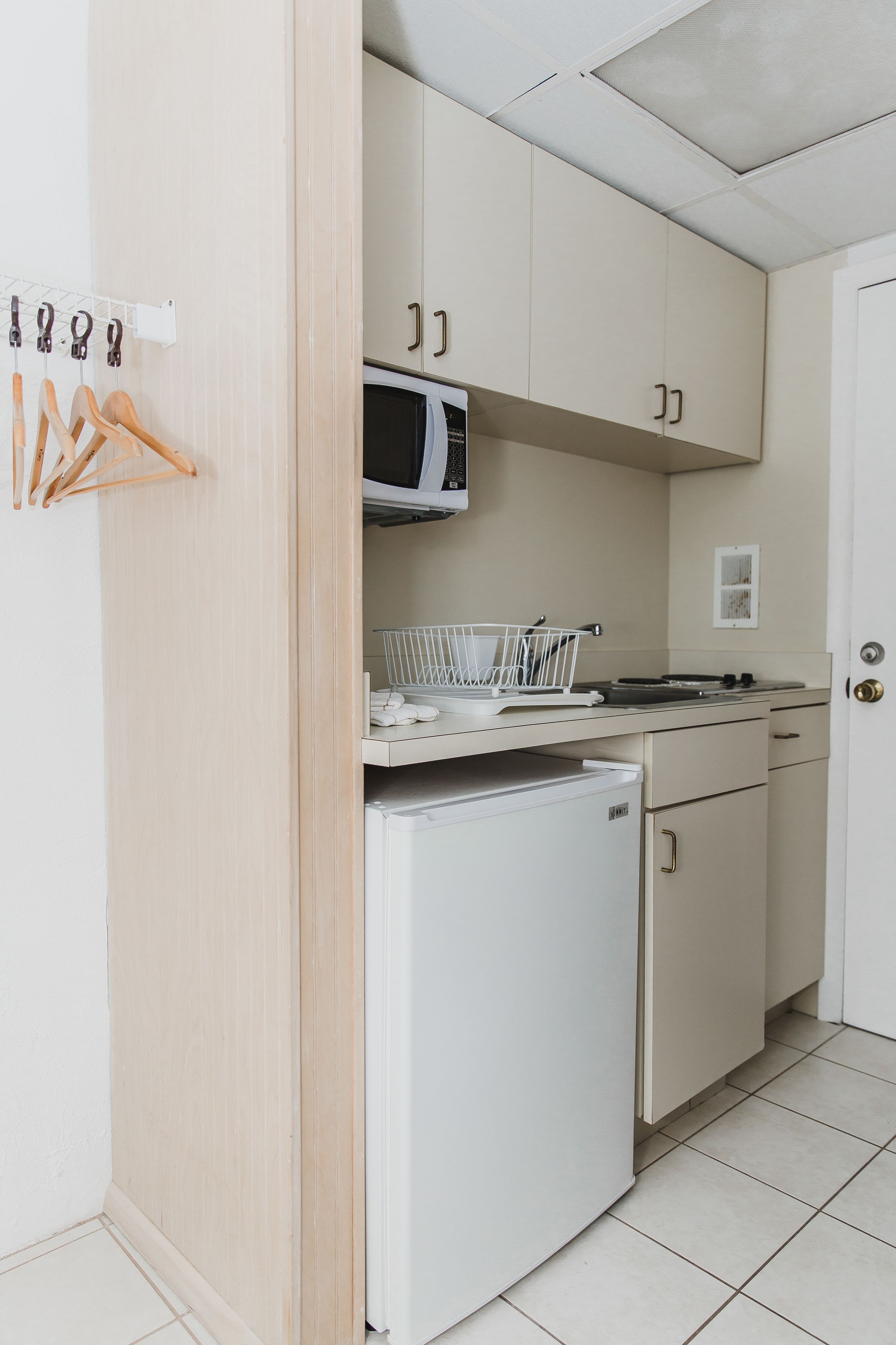 Eine kleine Küche mit Mikrowelle, kleinem Kühlschrank und Spüle.