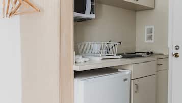 Eine kleine Küche mit Mikrowelle, kleinem Kühlschrank und Spüle.
