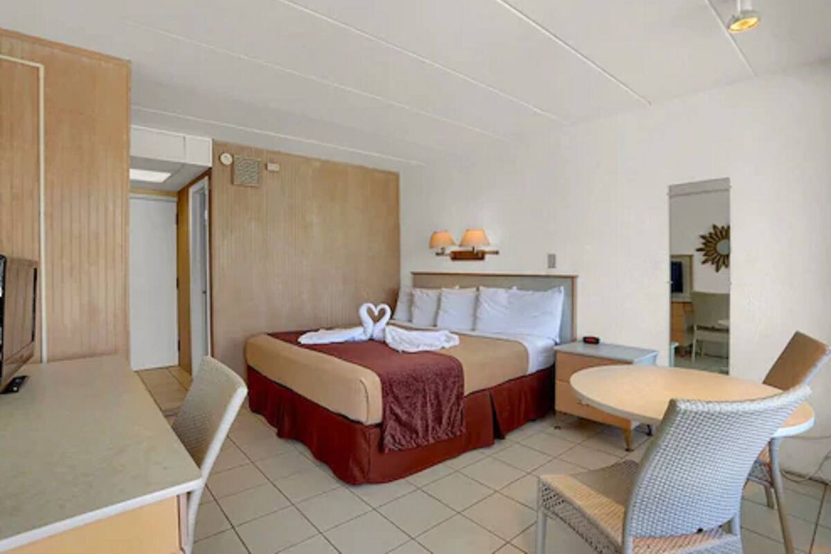 A hotel room with a bed, a desk, and a dining table with chairs.