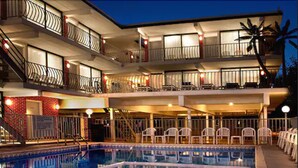 A multi-story hotel with a swimming pool, outdoor seating, and a staircase leading to the upper floors. - AA Heart of Wildwood Motels (Wildwood)