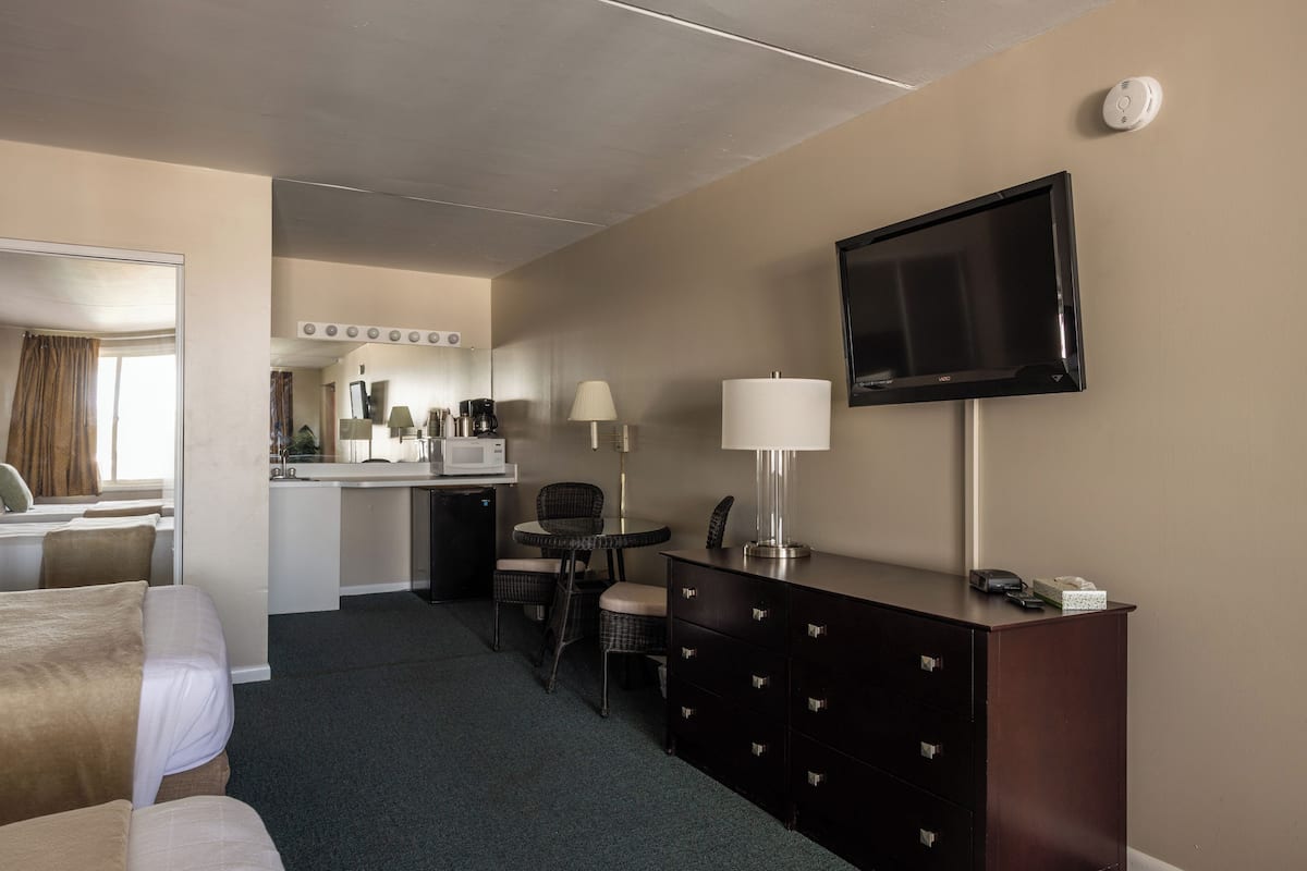 A hotel room with a bed, a desk with a chair, a television, a dresser, and a microwave.