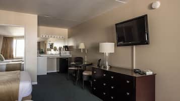 A hotel room with a bed, a desk with a chair, a television, a dresser, and a microwave.