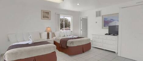 Habitación de hotel con dos camas, televisión, cómoda y ventana con vistas.