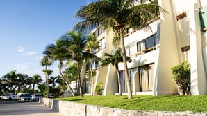 Un hotel moderno con fachada blanca, varios balcones y palmeras.