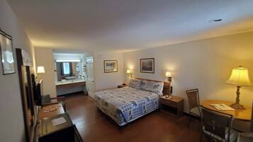 Une chambre d’hôtel comprenant un lit, des tables de chevet, un bureau, une chaise, un miroir et une porte.