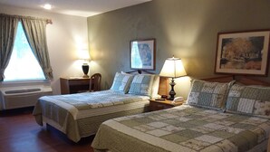 A hotel room with two beds, a desk, a chair, a window with curtains, and a painting on the wall. - Chatuge Mountain Inn (Hayesville)