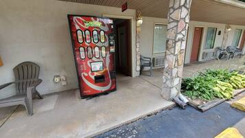 A vending machine with a Coca-Cola logo, a sign above it, and a chair to the left.