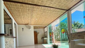 Un vestíbulo amplio con un diseño moderno, que incluye una puerta de cristal grande hacia un área exterior, una mesa de centro contemporánea y un sofá blanco.