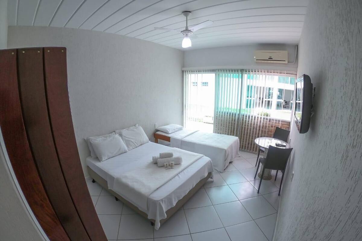 A hotel room with two beds, a dining area, and a TV on the wall.