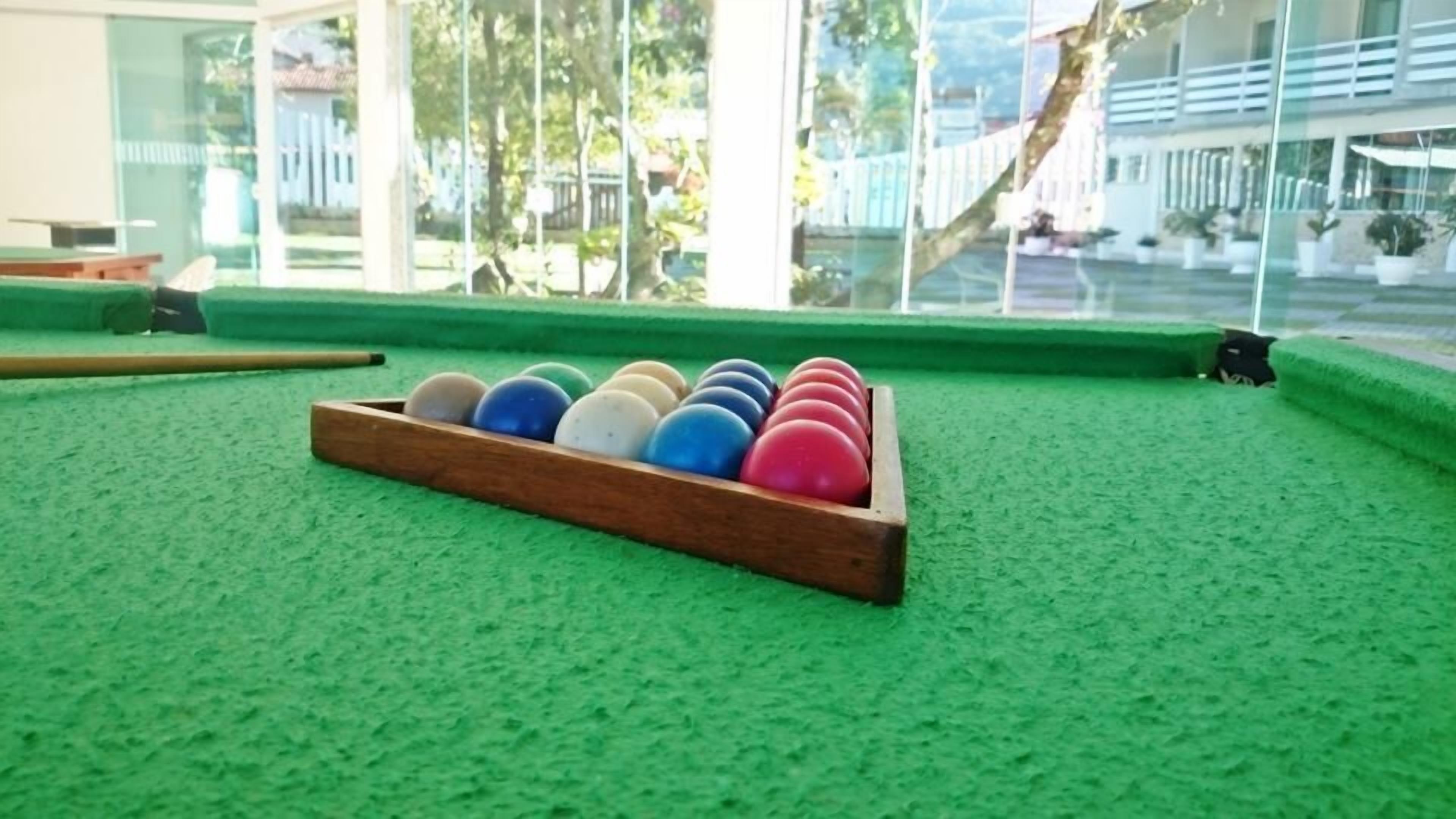 A pool table with a wooden rack holding billiard balls, a cue stick, and a green felt surface.