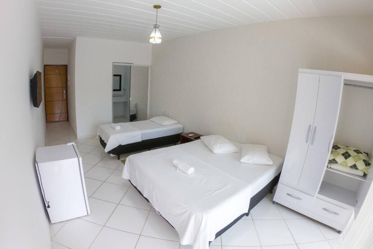 A bedroom with two beds, a wardrobe, and a small refrigerator.