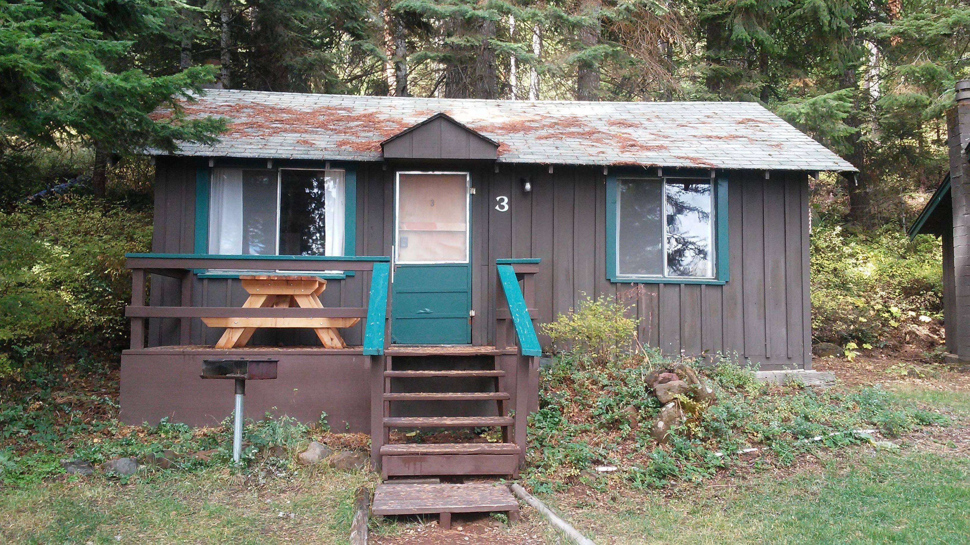 Eine kleine Holzhütte mit einem Picknicktisch und einer Treppe, die zur Tür führt.