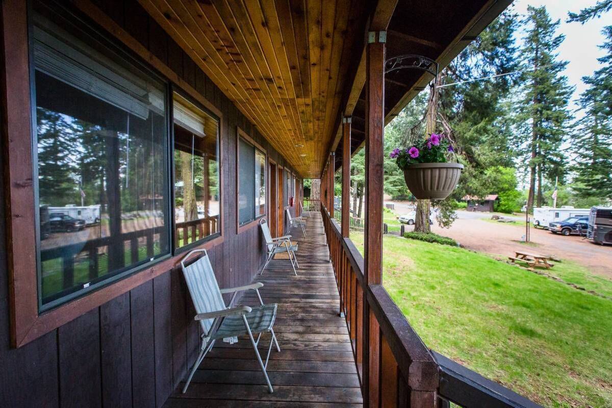 A wooden porch with a row of chairs and a hanging planter with flowers.