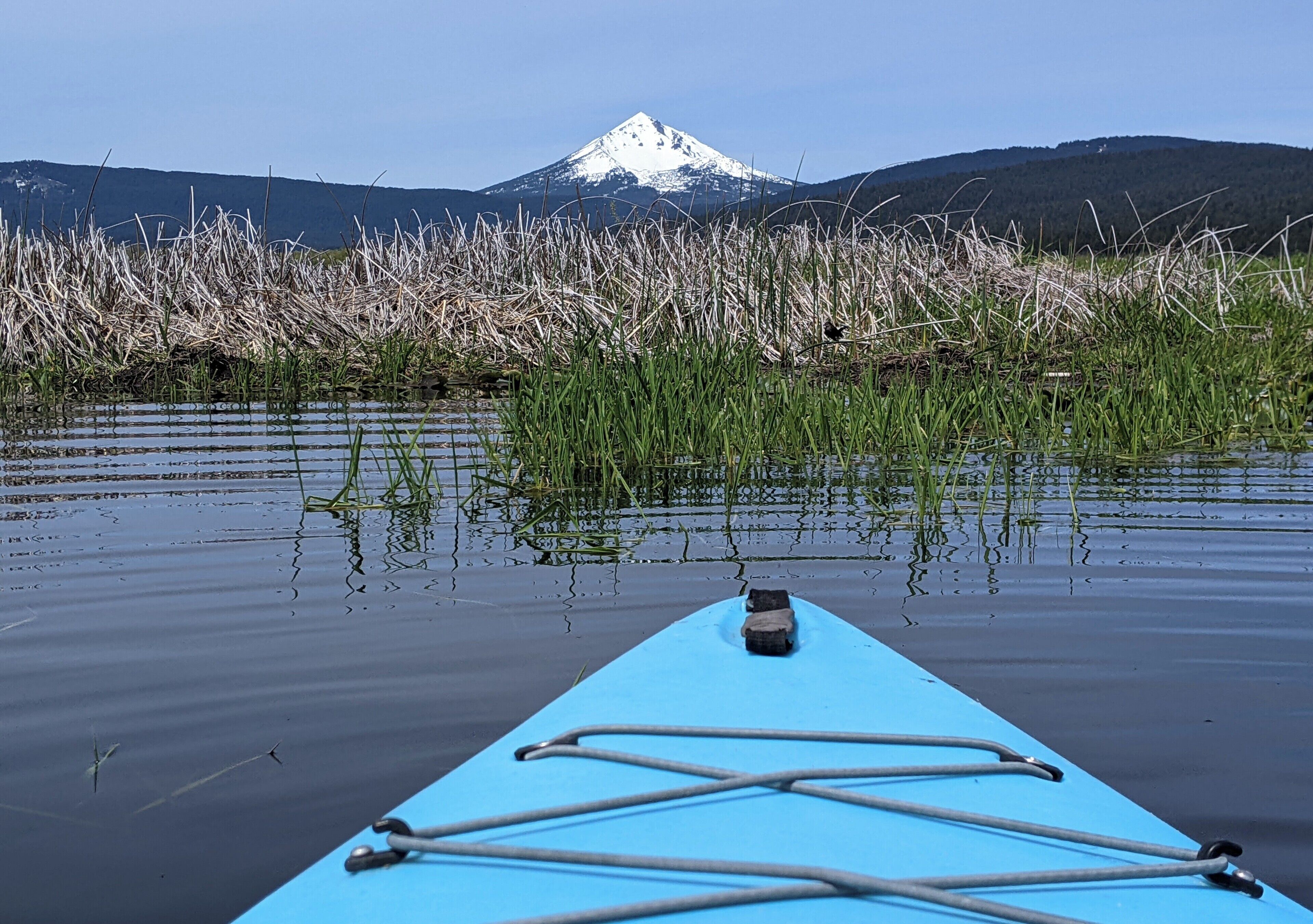 A kayak on calm water with a mountain in the background.
