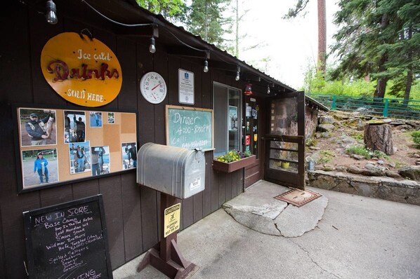 A rustic wooden building with a sign for 'Ice cold Drinks' and a 'Dinner 4:00-8:00PM' sign.